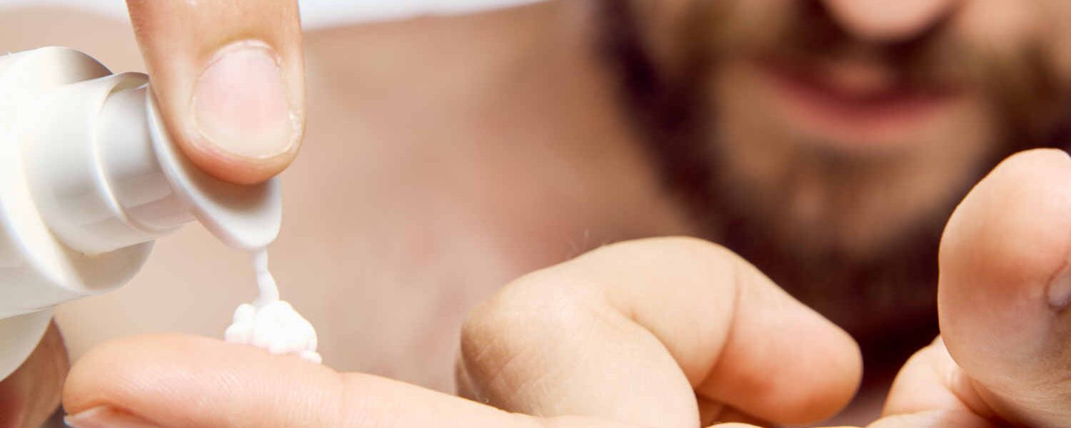 man dispensing body cream onto finger